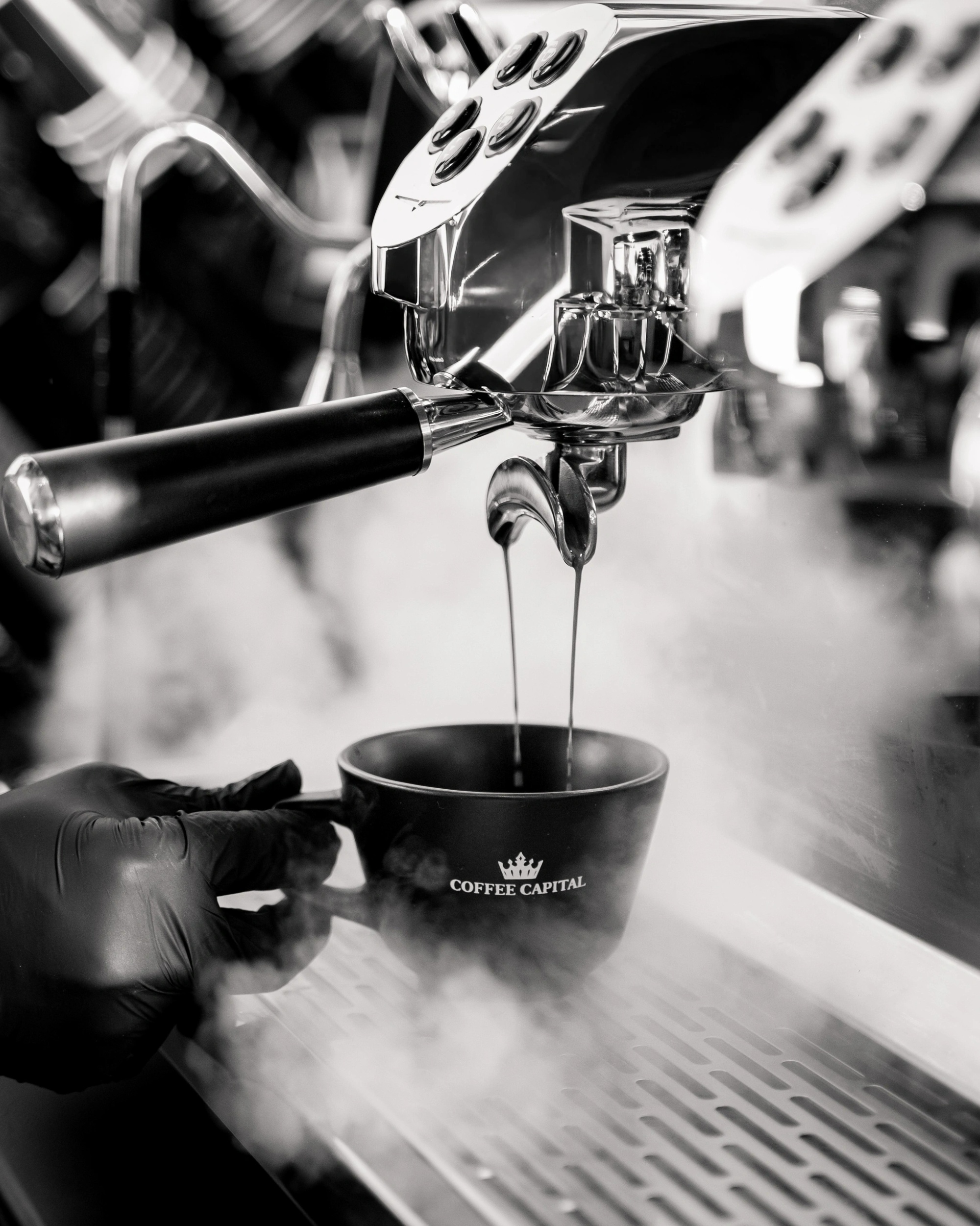 Espresso extraction into a Coffee Capital branded cup, black and white