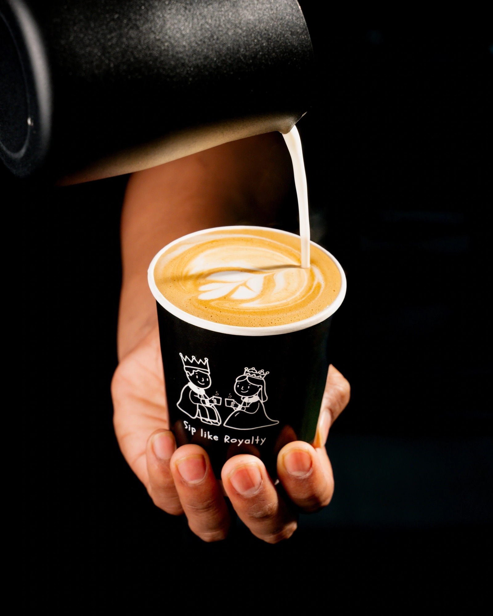 Barista pouring latte art into a Coffee Capital branded cup